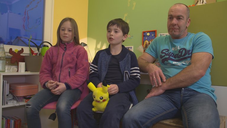 Ingo Fontaine sitzt mit seiner Tochter und seinem Sohn auf einer Bank im Kinderzimmer.