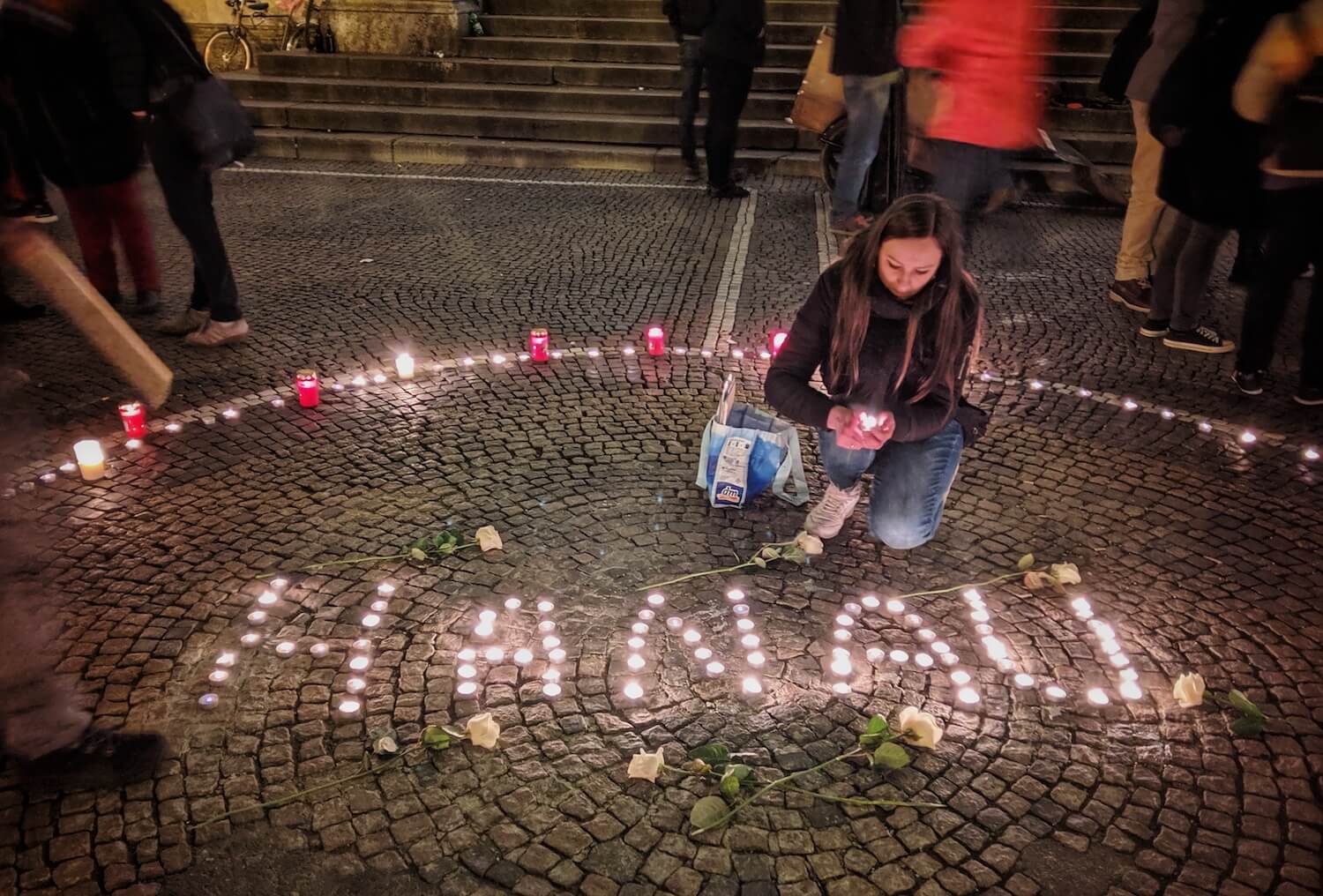 Eine Frau zündet in München zum Gedenken an die Opfer des Anschlags in Hanau Kerzen an.