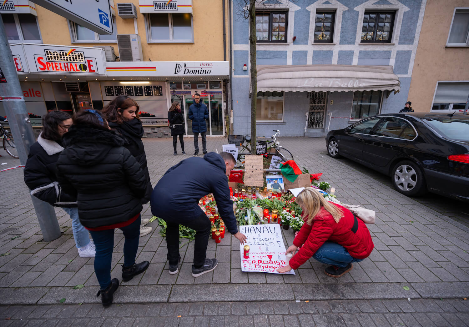 Menschen legen ein Plakat in der Nähe des Ortes in Hanau ab, an dem der Anschlag geschah.