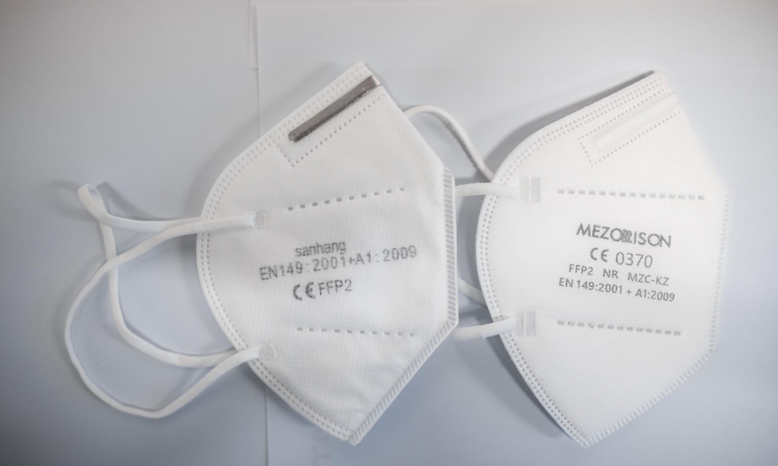 Zwei FFP2-Masken liegen auf einem Tisch. Die aufgedruckt CE Zertifizierung ist nur mit der vierstelligen Prüfnummer echt, die linke Maske zeigt eine vermutlich gefälschte CE-Zertifizierung. (Credit: Picture Alliance/ Dpa / Fabian Strauch)