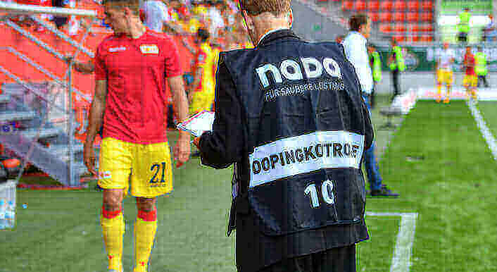 Ein Dopingkontrolleur der NADA steht am Spielfeldrand und wartet auf einen Fußballer