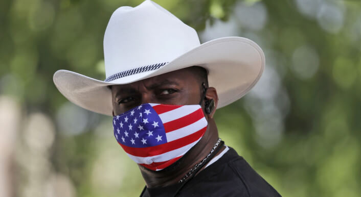 Mann mit Cowboyhut und Mund-Nase-Bedeckung mit dem Motiv der US-Flagge