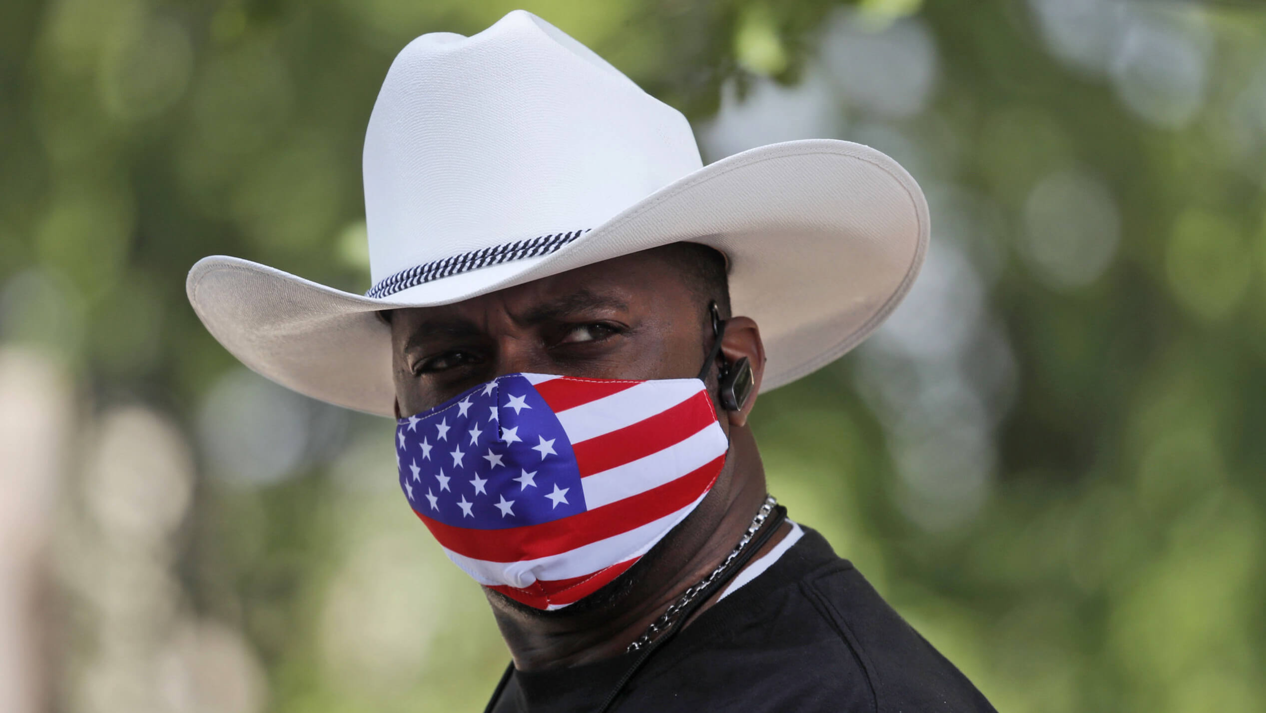 Mann mit Cowboyhut und Mund-Nase-Bedeckung mit dem Motiv der US-Flagge