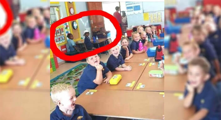 Weiße und schwarze Schulkinder sitzen an unterschiedlichen Tischen in einer Schule in Südafrika