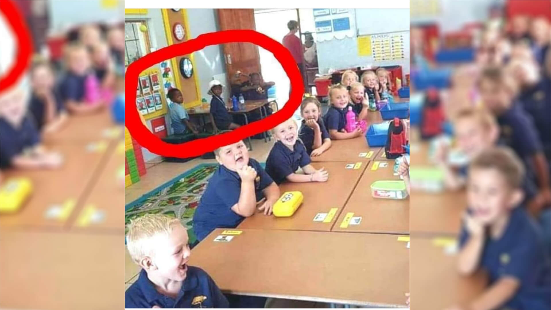 Weiße und schwarze Schulkinder sitzen an unterschiedlichen Tischen in einer Schule in Südafrika