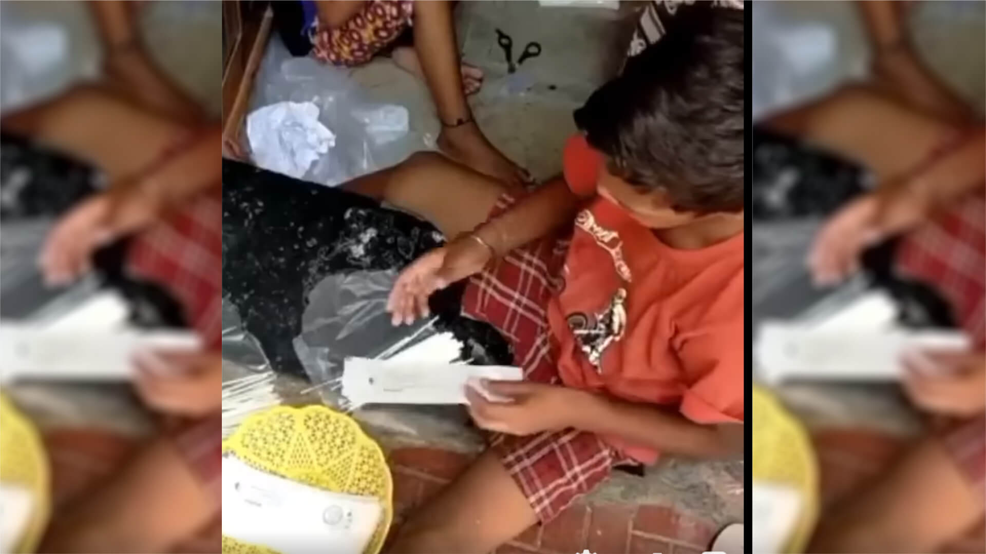 Kinder sitzen auf dem Boden einer Unterkunft in Indien und verpacken Abstrichstäbchen für Covid-19-Tests