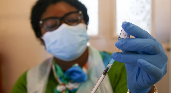 Eine Frau zieht eine Impfdosis auf eine Spritze
