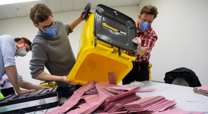 Wahlhelfer schütten eine Wahlurne für die Auszählung aus.