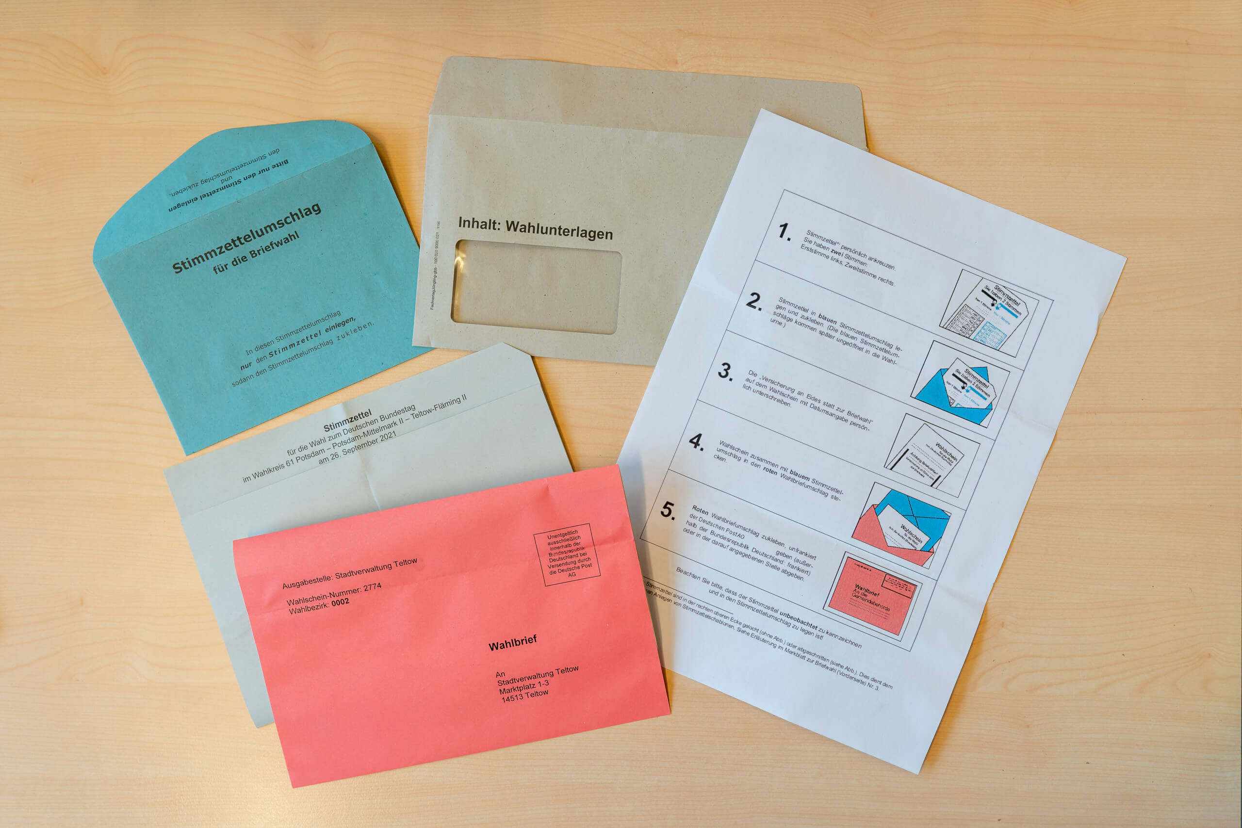 Briefwahlunterlagen für die Bundestagswahl 2021 bestehen aus dem Stimmzettel, dem blauen Stimmzettelumschlag, dem roten Wahlbriefumschlag und dem Wahlschein mit der eidesstattlichen Erklärung (nicht im Bild zu sehen).