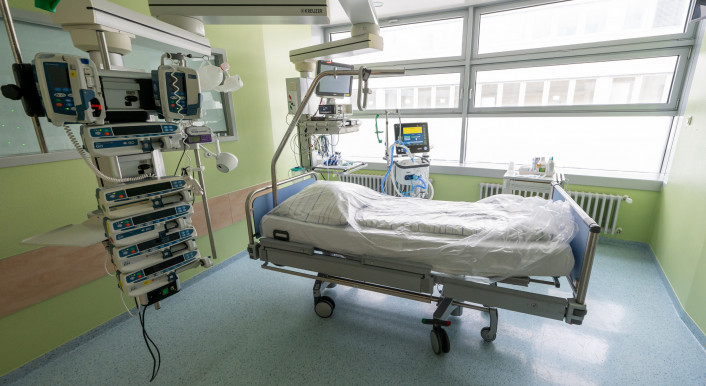 Bild eines leeren Krankenhausbettes umgeben von Monitoren.