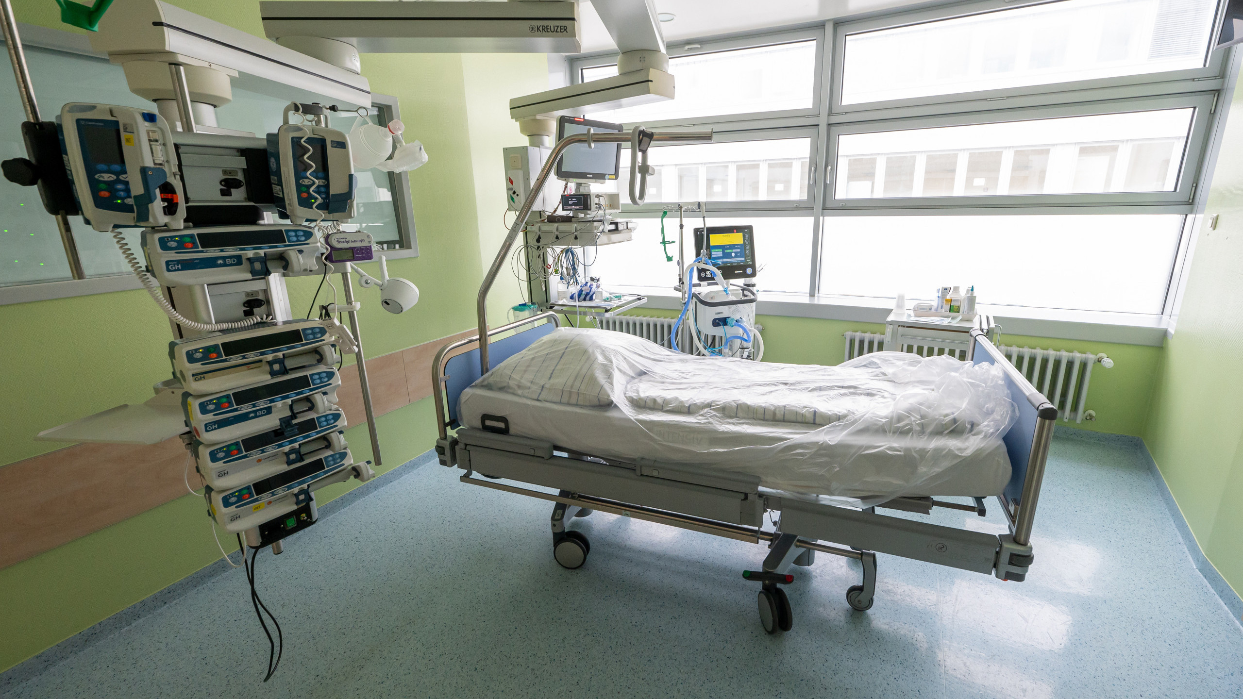 Bild eines leeren Krankenhausbettes umgeben von Monitoren.