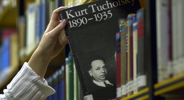 Jemand nimmt eine Biografie von Kurt Tucholsky aus einem Bücherregal.