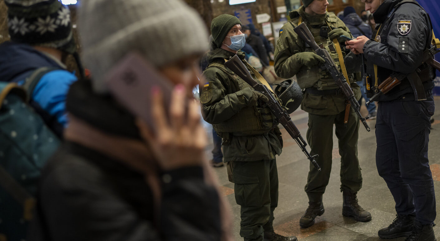 Ukrainische Soldaten stehen Wache, während Menschen am 24. Februar versuchen, den Kiewer Bahnhof zu verlassen (Quelle: Picture Alliance / Associated Press / Emilio Morenatti)