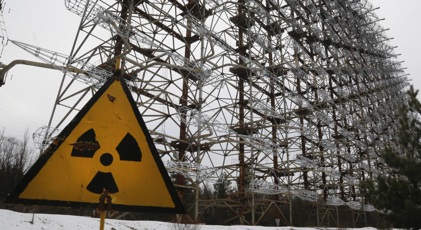 Ein Radarsystem aus der Sowjet-Zeit hinter einem Radioaktivistätsschild in Tschernobyl. Das Kraftwerksgelände in Tschernobyl wurde am 24. Februar 2022 von russischen Truppen eingenommen (Credit: Picture Alliance / Associated Press / Efrem Lukatsky)