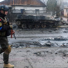 Ukrainischer Soldat vor einem ausgebrannten Panzer