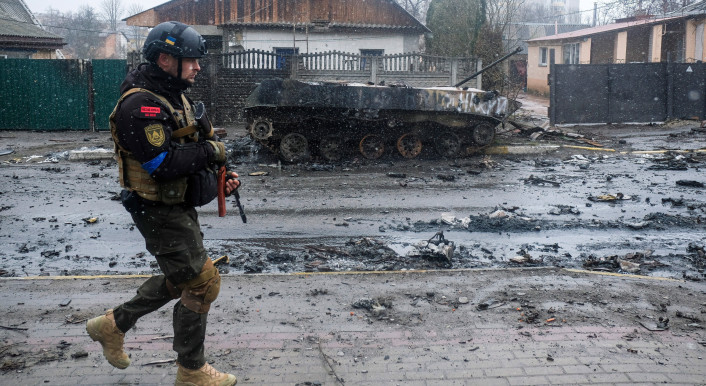 Ukrainischer Soldat vor einem ausgebrannten Panzer