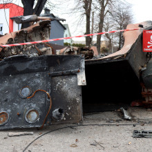 An einem zerstörten Panzer in Butscha hängt ein Schild, das vor Minen warnt.