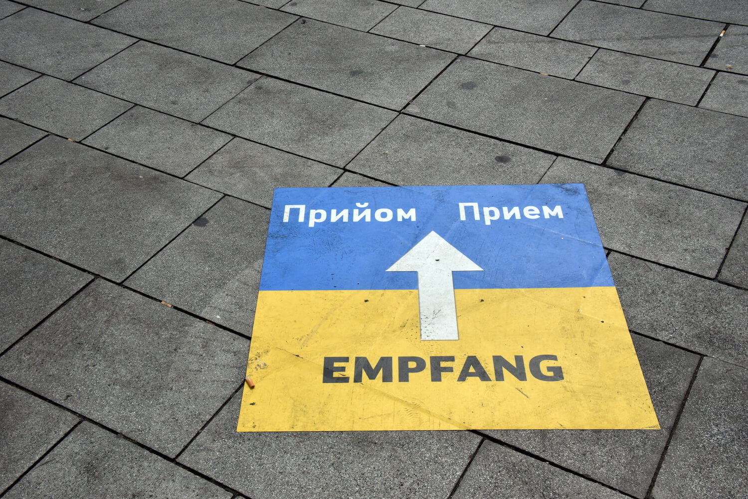 Eine ukrainische Flagge ist auf den Boden gemalt, mit einem Weghinweis zum Empfang für Flüchtlinge.