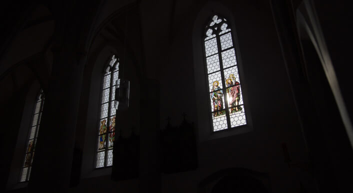 Licht fällt durch bunte Kirchenfenster ins Dunkel eines Kirchenschiffs. Foto: Ivo Mayr / Correctiv