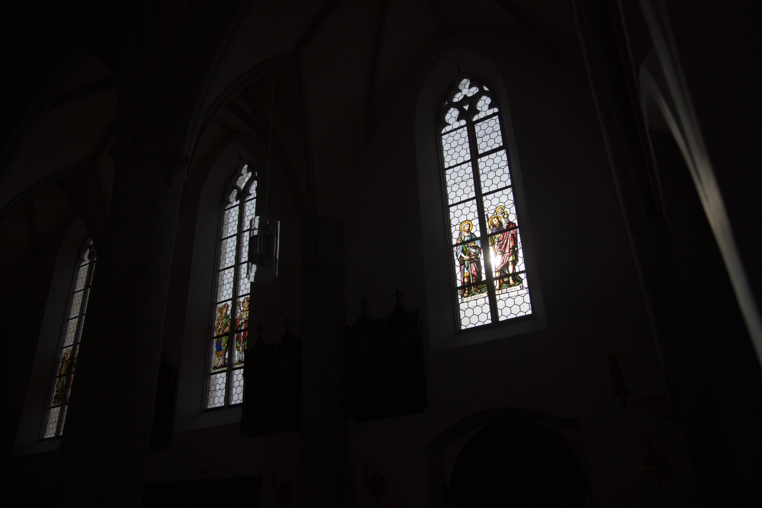 Licht fällt durch bunte Kirchenfenster ins Dunkel eines Kirchenschiffs. Foto: Ivo Mayr / Correctiv