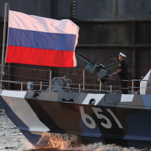 Russische Fahne und ein Seemann auf einem russischen Kriegsschiff.