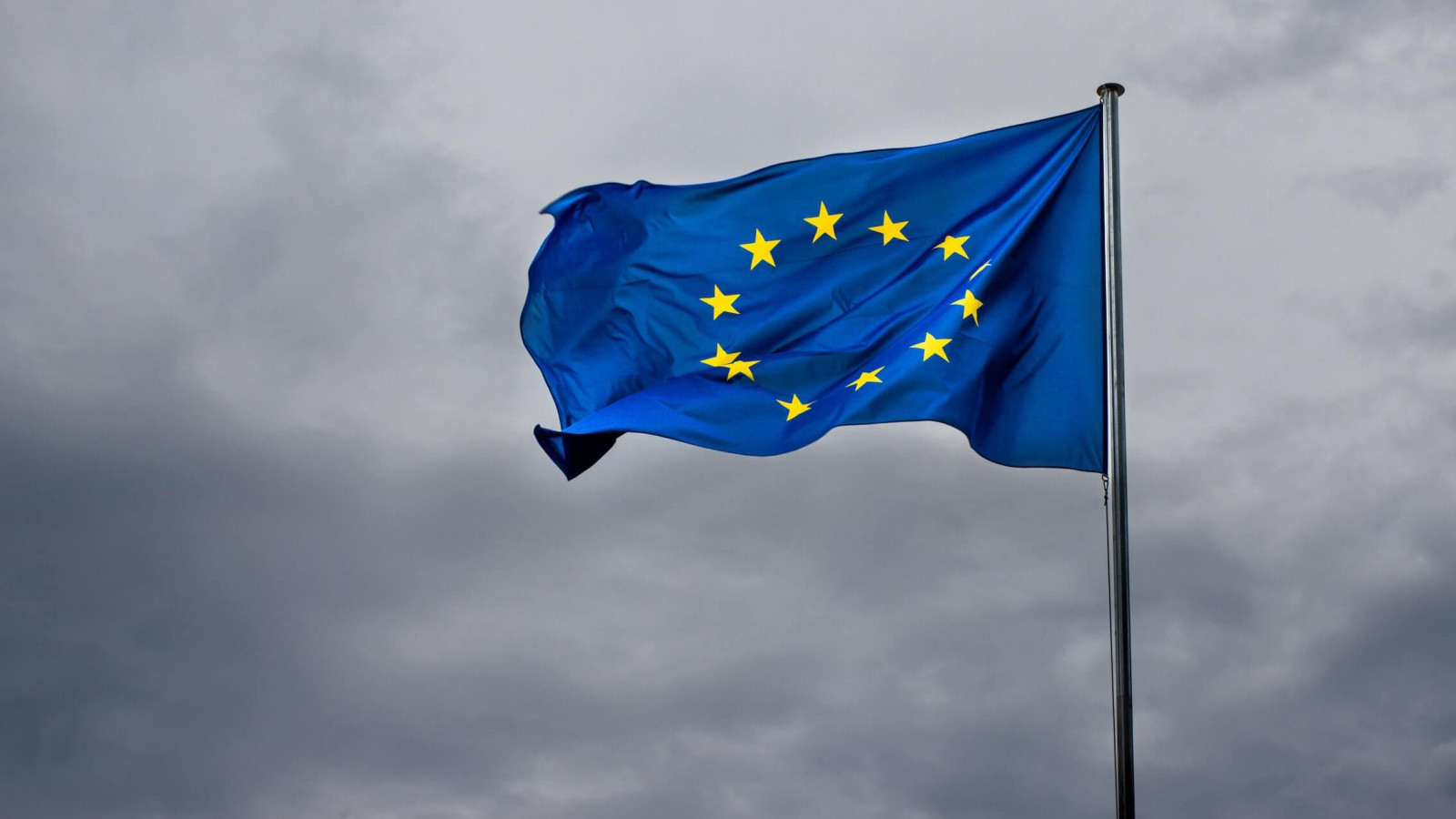 Eine wehende EU-Flagge vor einem bewölkten Himmel
