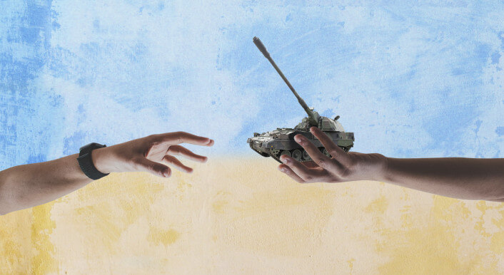 Symbolbild: zwei Hände tauschen eine Kriegswaffe vor der Fahne der Ukraine