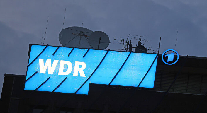Ein Logo des WDR (Westdeutscher Rundfunk) leuchtet auf dem Dach des Senders.