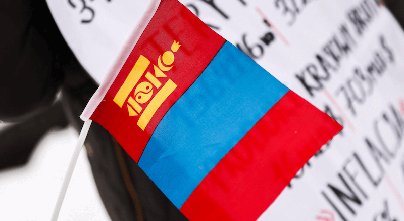 Die Flagge der Mongolei vor einem Schild.