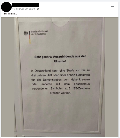 Ein Plakat, auf dem steht: „In Deutschland kann eine Strafe von bis zu drei Jahren Haft oder einer hohen Geldstrafe für die Demonstration von Hakenkreuzen oder anderen mit dem Faschismus verbundenen Symbolen (zum Beispiel SS-Zeichen) erhalten werden“
