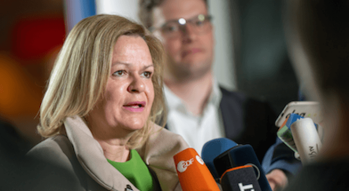 Ein Foto von Nancy Faeser, wie sie in mehrere Mikrofone spricht.