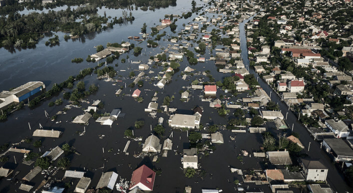 Eine Luftaufnahme zeigt eine ganze Stadt, die unter Wasser steht, nur die Dächer der Häuser ragen hervor.