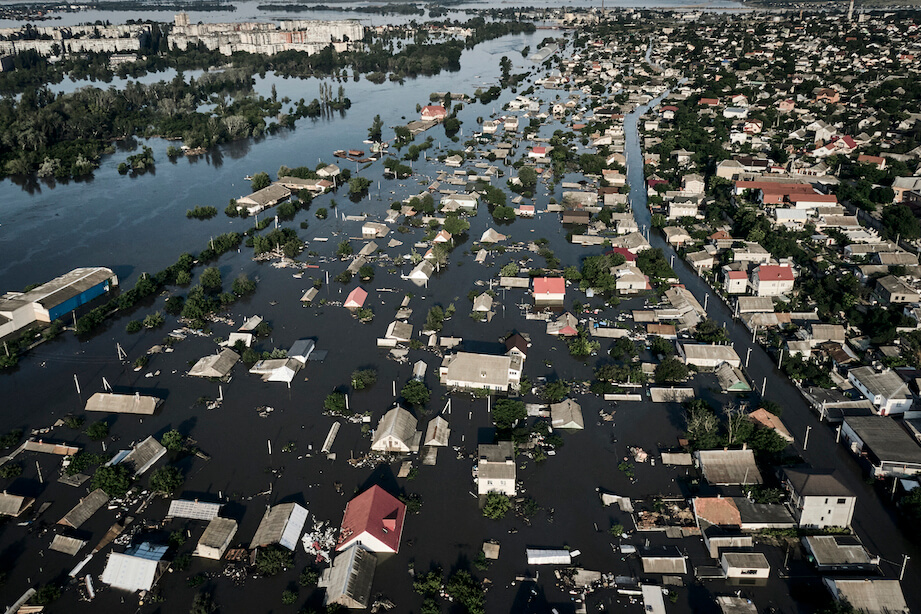 Eine Luftaufnahme zeigt eine ganze Stadt, die unter Wasser steht, nur die Dächer der Häuser ragen hervor.