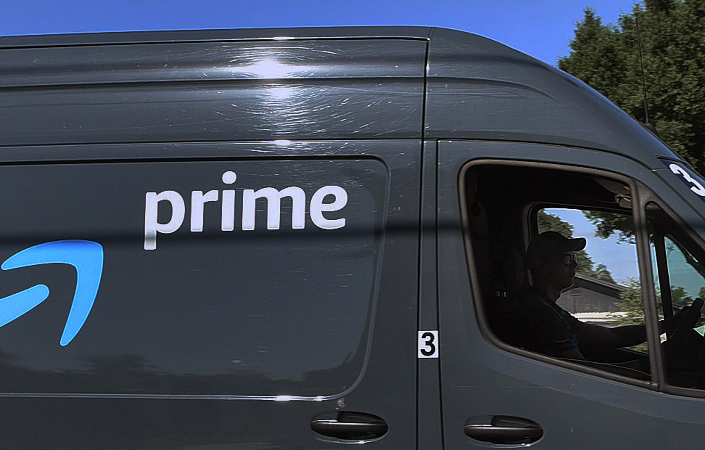 Ein Fahrer am Steuer eines Kleintransporters mit Amazon-Branding.