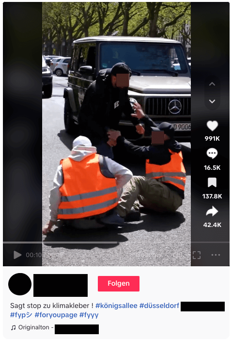 Eine weitere Szene aus dem Video, zu sehen ist, wie ein Mann einen anderen Mann in Warnweste von der Straße zieht