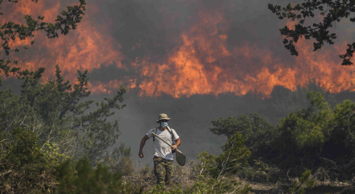 Person vor einem brennendem Wald auf der Insel Rhodos in Griechenland am 25. Juli 2023.