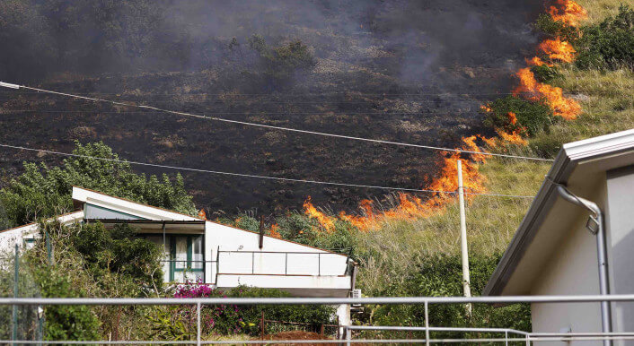 Flammen hinter Häusern in Capaci, in der Nähe der sizilianischen Hauptstadt Palermo am 26. Juli 2023.