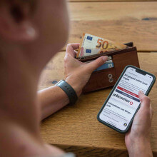 Person hält ein Smartphone, das ein Webseite der Bundesagentur für Arbeit zeigt.
