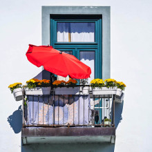 Symbolbild: Ein roter Schirm an einem Balkon