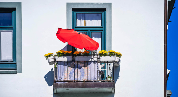 Symbolbild: Ein roter Schirm an einem Balkon