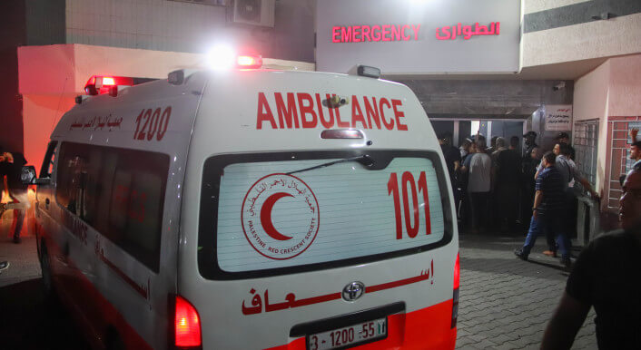 Ein Krankenwagen mit arabischer Schrift, dem Symbol des roten Halbmonds und der englischen Aufschrift Ambulance vor der Notaufnahme des Al-Shifa Krankenhauses in Gaza bei Dunkelheit.