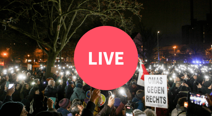Bild einer Demonstration; zu sehen sind Menschen, die Schilder und ihre Smartphones mit eingeschaltetem Blitzlichtnach oben halten. In der Bildmitte ist eine roter Kreis mit der Aufschrift „Live“ zu sehen.