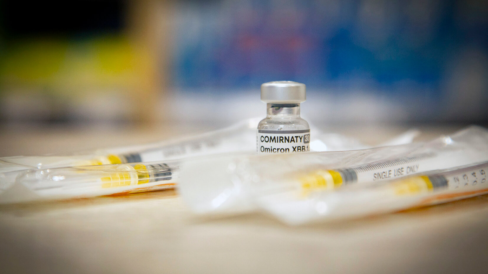 Impfstoff auf einem Tisch, daneben mehrere verpackte Spritzen