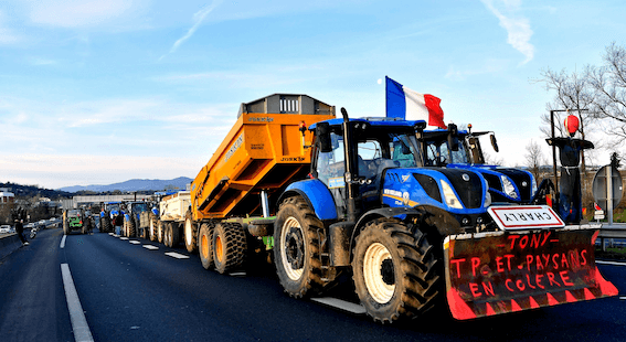 Auf einem Bild ist ein Konvoi aus Traktoren zu sehen, der vorderste trägt die französische Flagge.