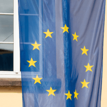 Foto einer Europa-Flagge vor einem Fenster.