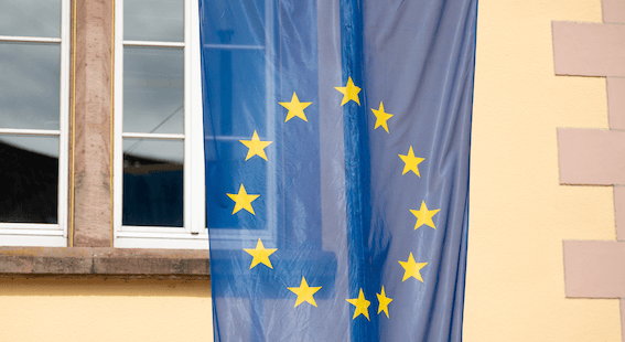 Foto einer Europa-Flagge vor einem Fenster.