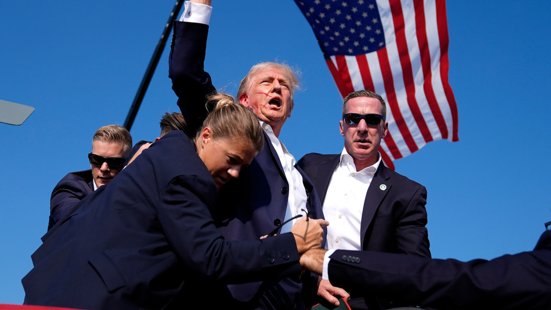 Originalfoto der Situation als Trump von der Bühne geführt wird von mehreren Beamten des Secret Service