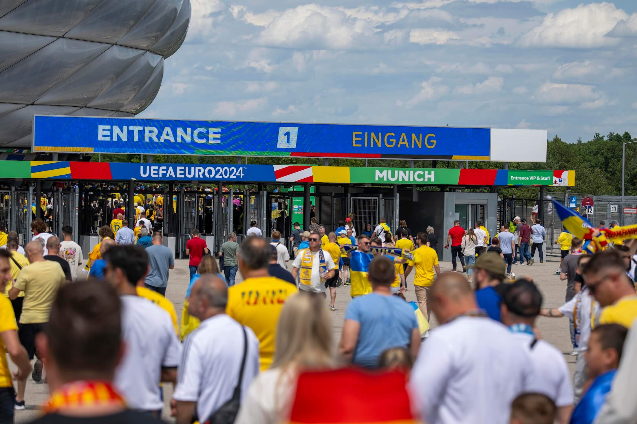 Eingangsbereich der Allianz Arena in München. Fans in gelben Trikots strömen zum Stadion, die Tickets für die EM 2024 bekommen haben.