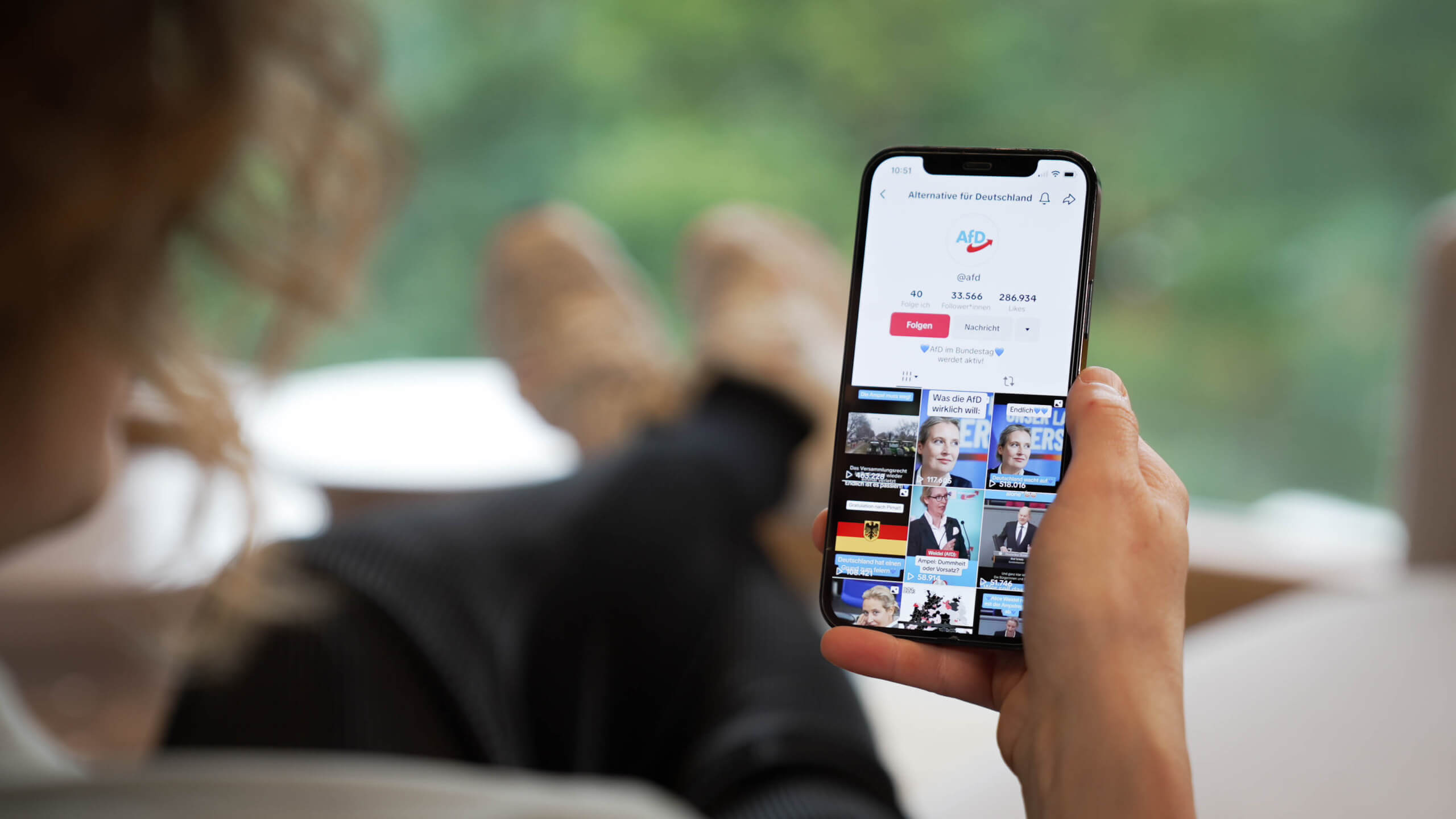 Jemand sitzt am Handy und guckt auf ein Tiktok-Profil mit AfD-Logo.