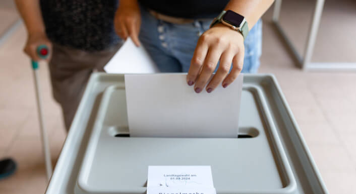 Eine Frau wirft einen Wahlschein in eine Urne
